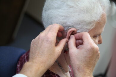 An audiologist fitting a hearing aid on elderly patient